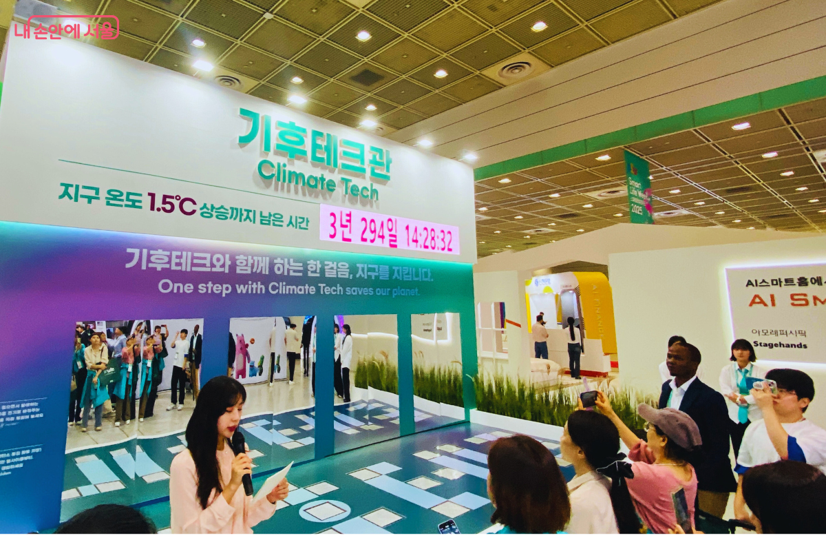 '기후테크관' 부스에서 시민들이 체험형 전시에 참여하고 있는 모습. '지구 온도 1.5℃ 상승까지 남은 시간'을 보여주는 디지털 타이머가 위기감을 고조시키며, 시민들은 도슨트의 설명에 귀 기울이며 기후 위기 대응 기술을 관람하고 있다.