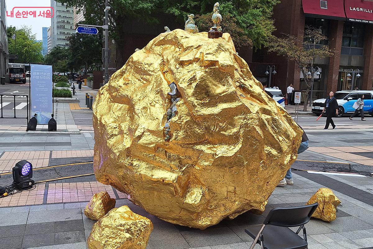 <그곳에 있었다_청계천 2025>는 현대미술 작가 이수경의 신작으로, 돌에 금박 옷과 도자기를 입혀 풍요와 번영을 기원하는 의미를 담았다. ©이혜숙