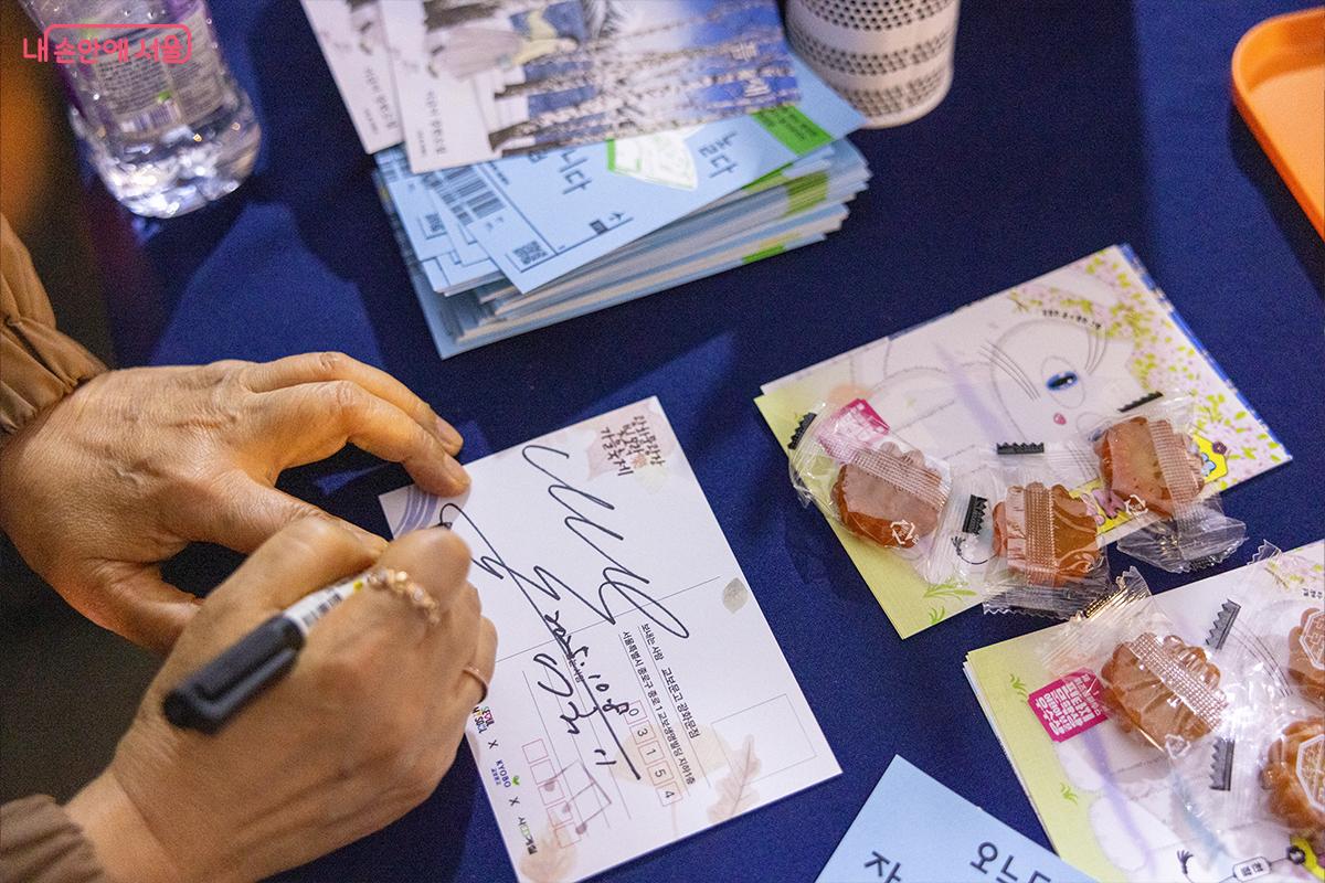 광화문광장 특설무대에서 열린 ‘빛모락 가을축제’ 저자 강연회에서 소설가 이금이 작가가 사인하고 있는 장면 ⓒ장신자