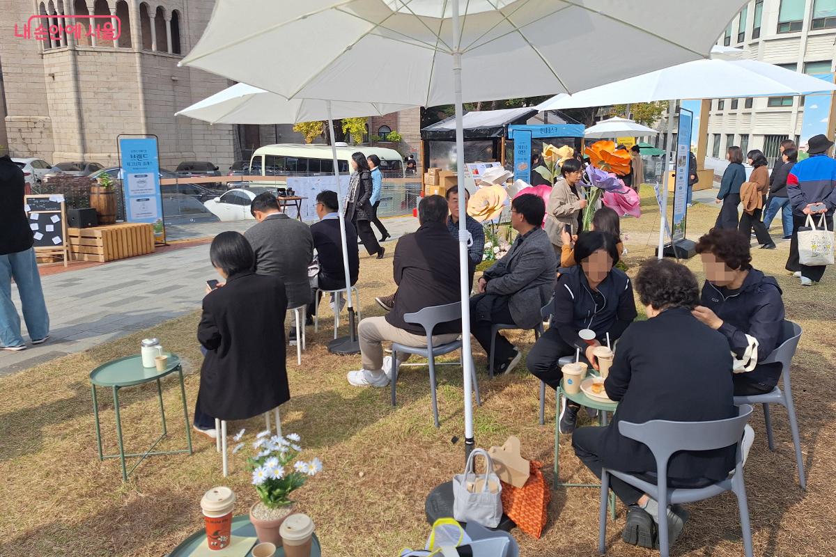 시민들이 커피를 마시며 버스킹을 즐기고 있다. ©백승훈