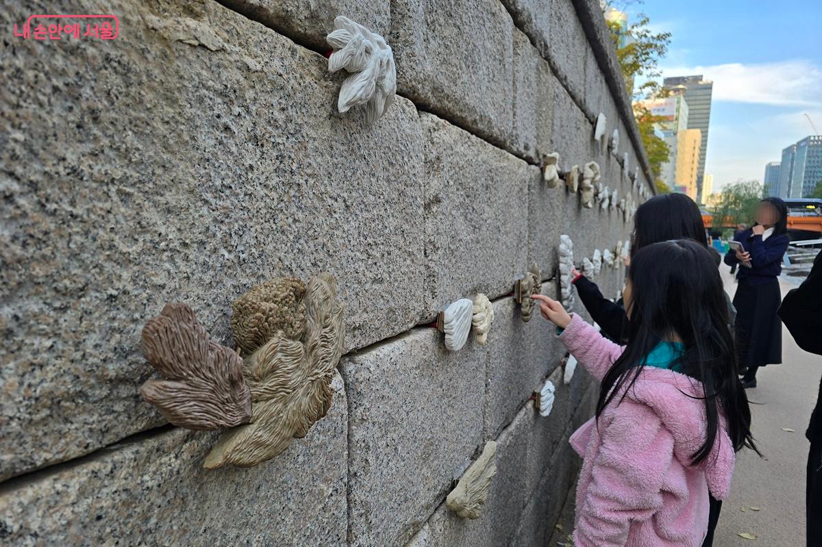 아이들이 전명은 작가의 &lsquo;청계초록: 눈길 손길&rsquo; 작품의 질감을 촉각으로 느끼고 있다. &copy;조성희