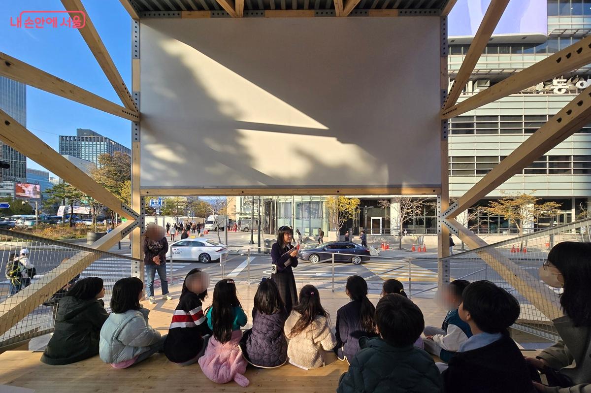 &lsquo;커넥천 파빌리온&rsquo; 작품 속 다리에 앉아서 설명을 듣는 아이들 &copy;조성희