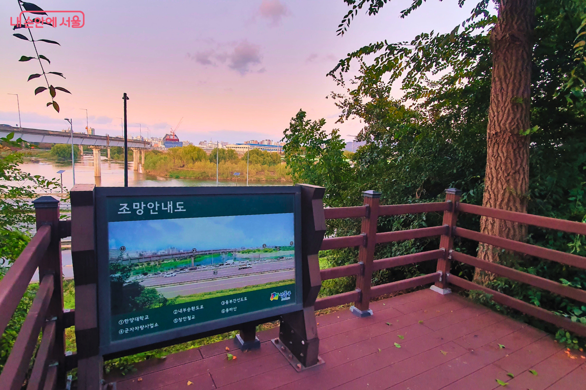 송정제방길에 설치된 나무 데크 조망대와 '조망안내' 표지판의 모습. 조망안내판에는 '한양대학교', '내부순환도로', '용비교' 등 이곳에서 볼 수 있는 주요 지점들이 사진과 함께 안내되어 있다. ©양정화