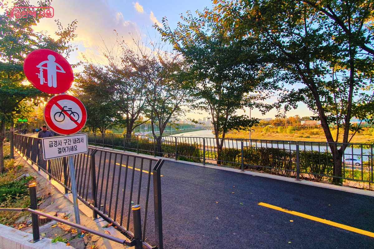 송정제방길의 보행자 전용 산책로 구간을 보여주는 사진. '금연·금주 구간', '자전거 통행 금지' 표지판이 명확히 설치되어 있어 보행자가 안전하게 걸을 수 있음을 강조한다. 멀리 중랑천과 강 건너편 억새숲이 보인다. ©양정화