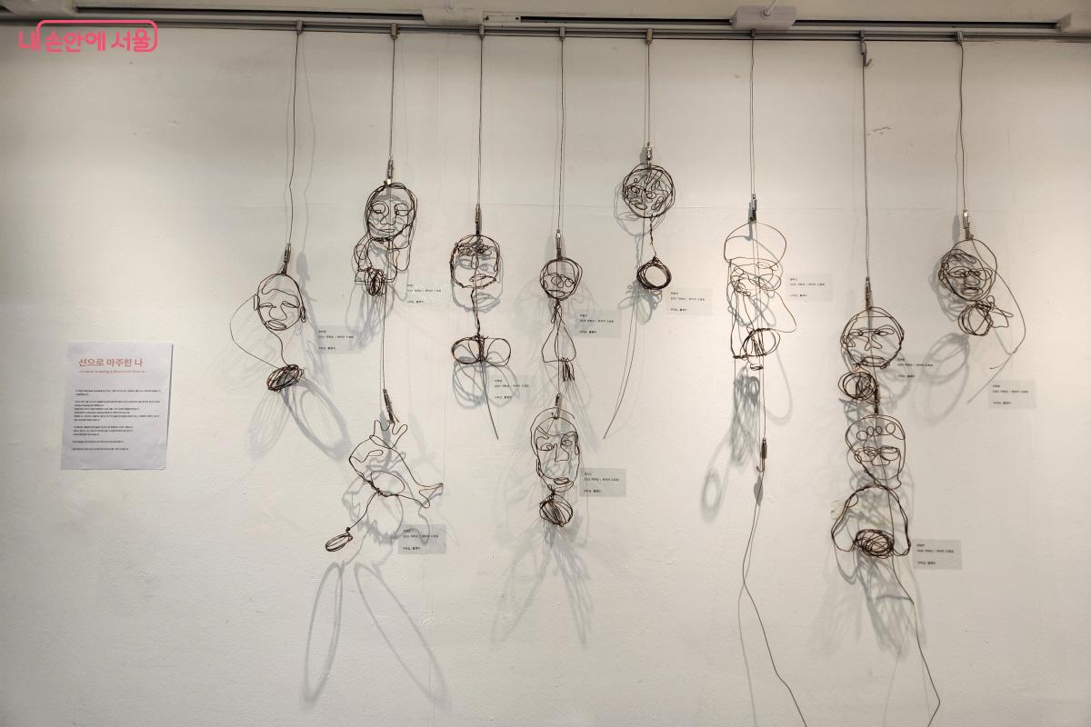 전시장 입구 벽면에 철선으로 제작한 자화상 얼굴 작품, &lsquo;선으로 마주한 나&rsquo; &copy;윤혜숙