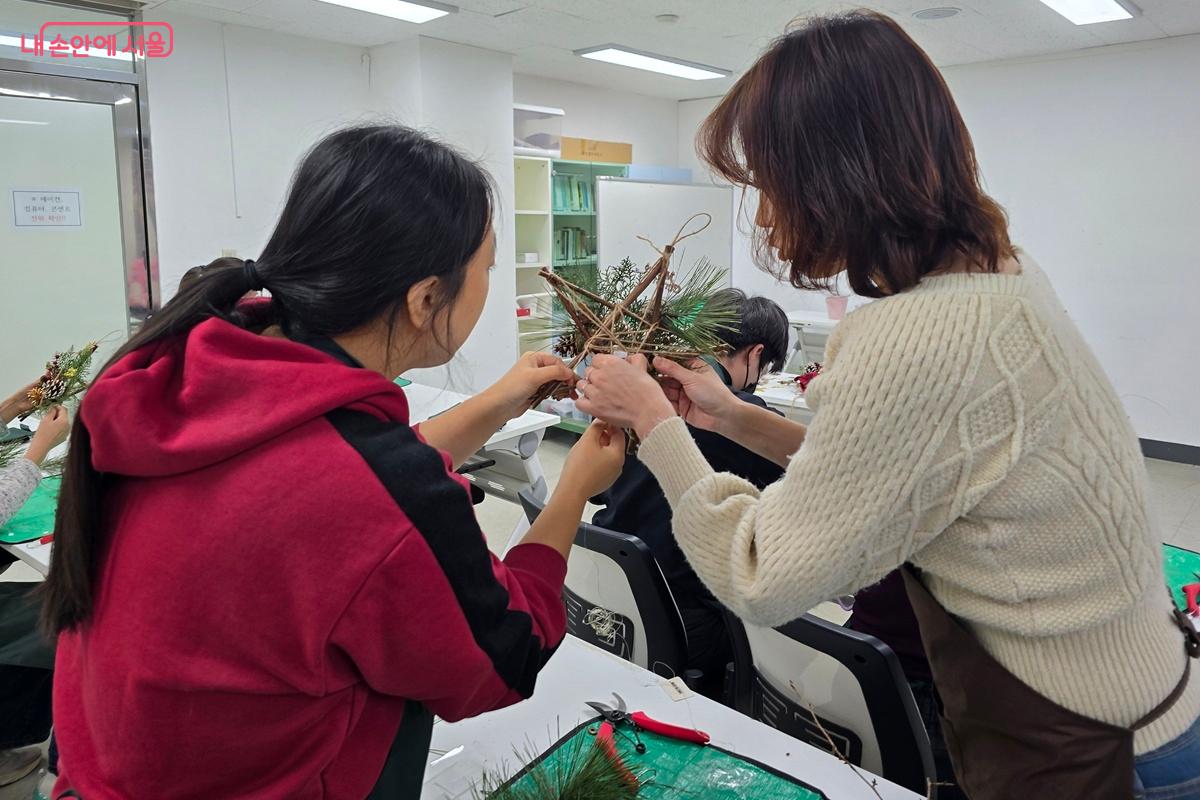크리스마스 오너먼트 만들기에 집중하고 있는 참여자와 강사 ©조성희