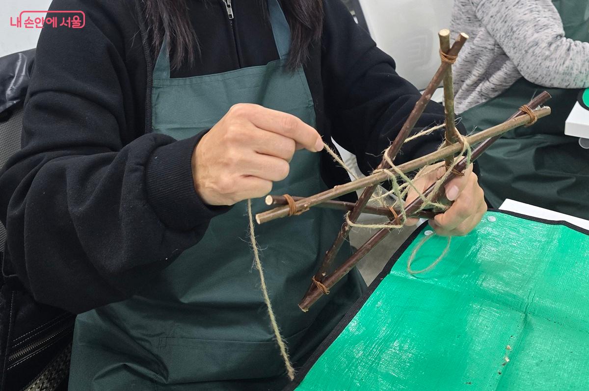 별 구조물을 완성한 후 마끈으로 엮어서 재료를 붙일 공간을 만들고 있다. ©조성희