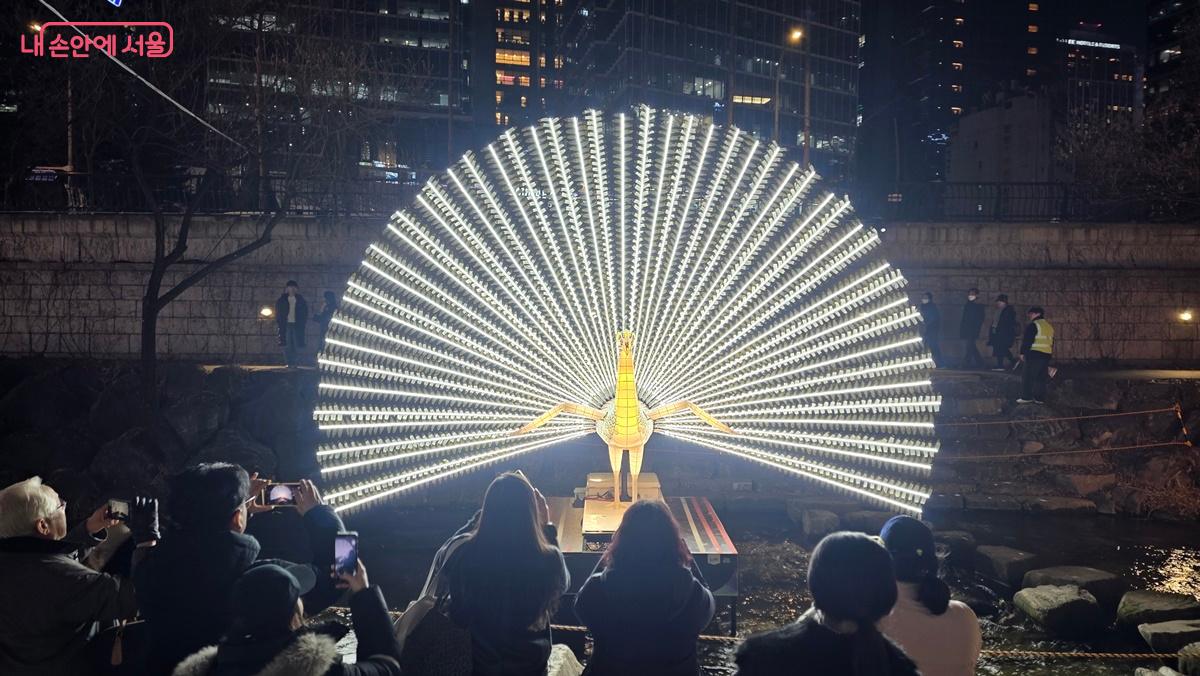 날개짓 하는 공작새 조형물 앞에는 인증샷 행렬이 길게 이어진다