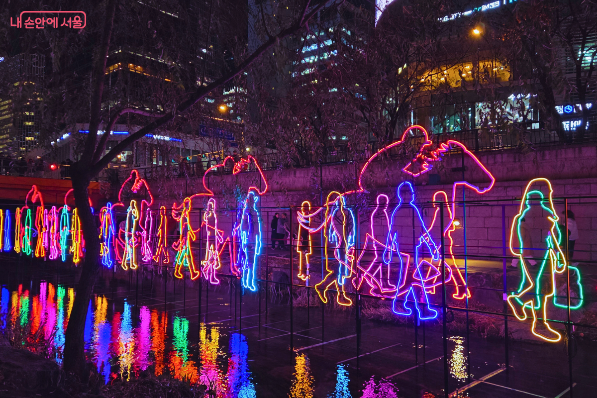 청계천 2구역에 설치된, 다양한 사람들의 실루엣을 네온 빛으로 표현한 조형물. 걷거나 짐을 든 사람들의 윤곽이 핑크색, 파란색, 노란색, 보라색 등 화려한 네온 컬러로 밝게 빛나며 청계천 물 위에 반사되고 있다. 이는 마치 서울 시민들의 바쁜 일상을 경쾌하게 표현하는 듯하며, 청계천변을 따라 길게 이어져 있다.