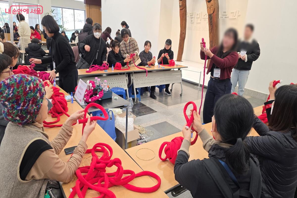 어른도 아이도 같이 참여하고 있는 &lsquo;팥죽 리스 만들기&rsquo;ⓒ이선미