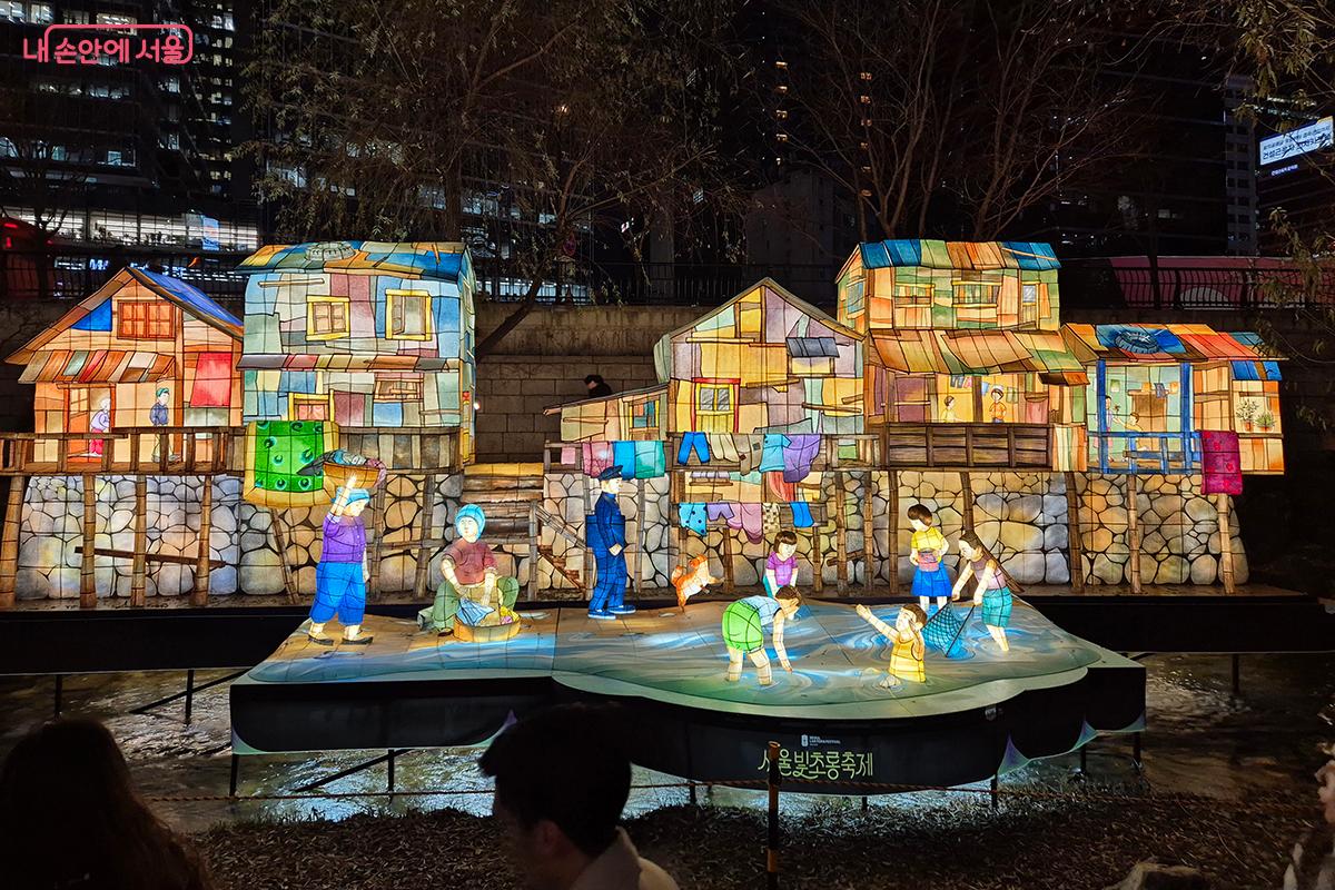 과거의 청계천에서 빨래를 하는 아낙들과 가방을 메고 등교하는 학생들