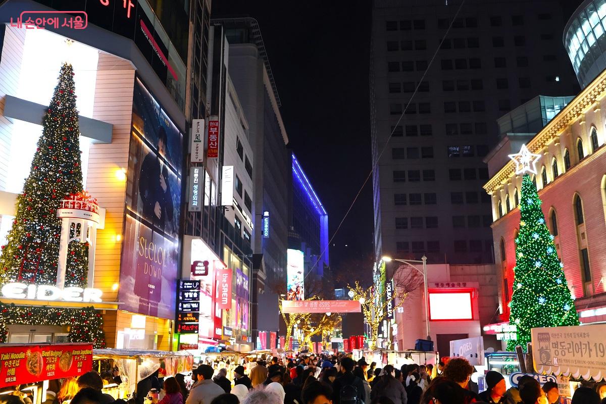 주변 건물의 네온과 어우러진 불빛은 명동 밤 거리를 한층 더 화사하게 빛나게 하며, 걷는 이들의 표정까지 환하게 비춘다. ©이봉덕