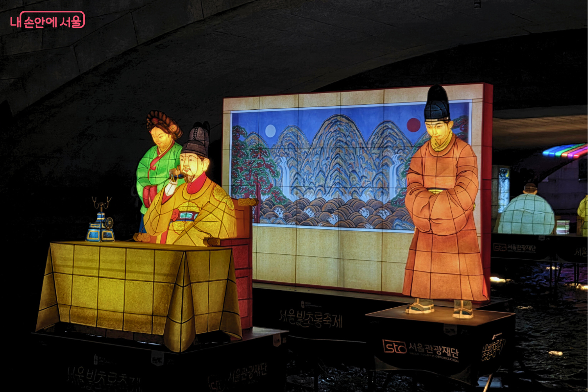 청계천 1구역에 설치된, 근대 개화기 시기의 모습을 담은 전통 등불 조형물. 조선시대 왕 복식을 한 인물이 탁자에 놓인 앤티크 스타일의 최초의 전화기 모습을 재현하고 있다. 왕 옆에는 상궁과 신하가 서 있고, 뒤편 배경 등에는 해와 달, 산이 그려진 병풍 그림이 배치되어 있다. 유등들은 주황색, 노란색, 녹색 등의 색으로 따뜻하게 빛나며, 근대의 시작을 표현하고 있다.