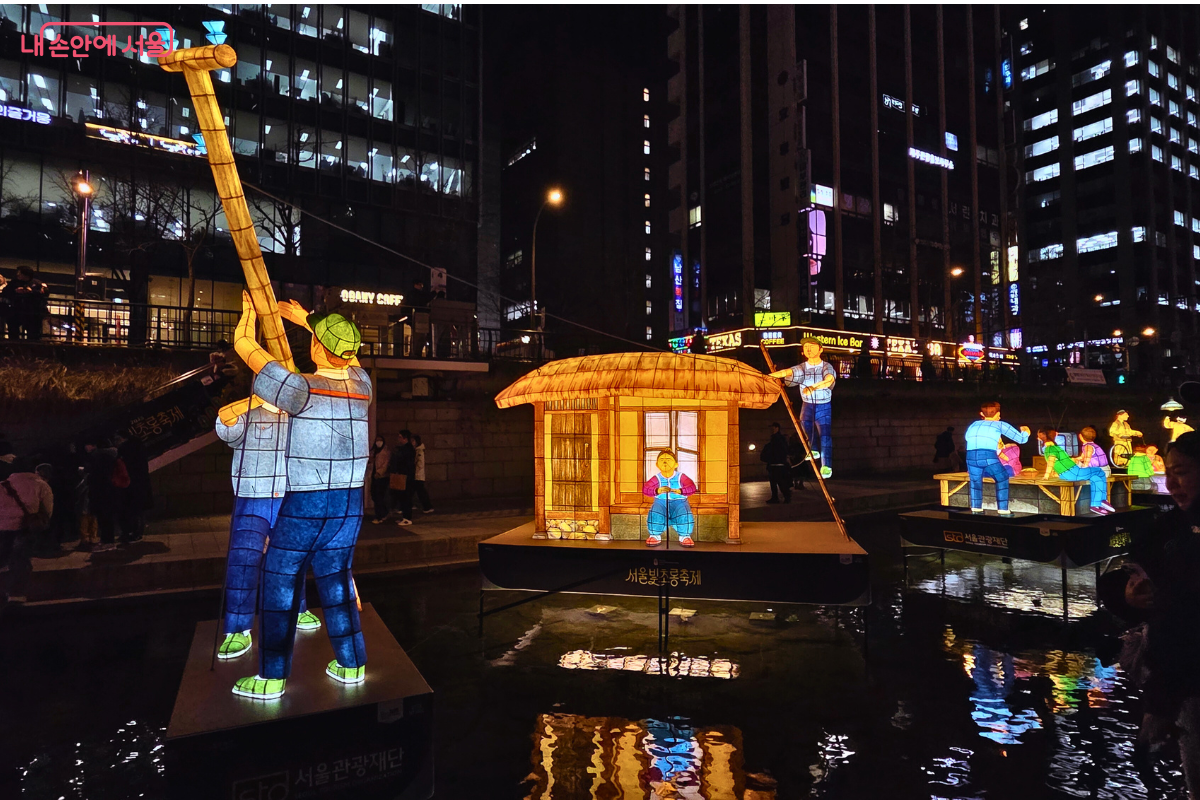 청계천 1구역에 설치된, 일상생활을 주제로 한 전통 등불 조형물. 두 명의 인물이 전신주를 세우고 있는 모습을 재현한 유등이 청계천 물 위에 떠 있다. 인물들은 푸른색과 노란색 계열의 옷을 입고 있으며, 초가집은 따뜻한 노란빛을 내고 있다. 이는 과거의 정겨운 일상을 '빛의 선물'로 표현하고 있다.