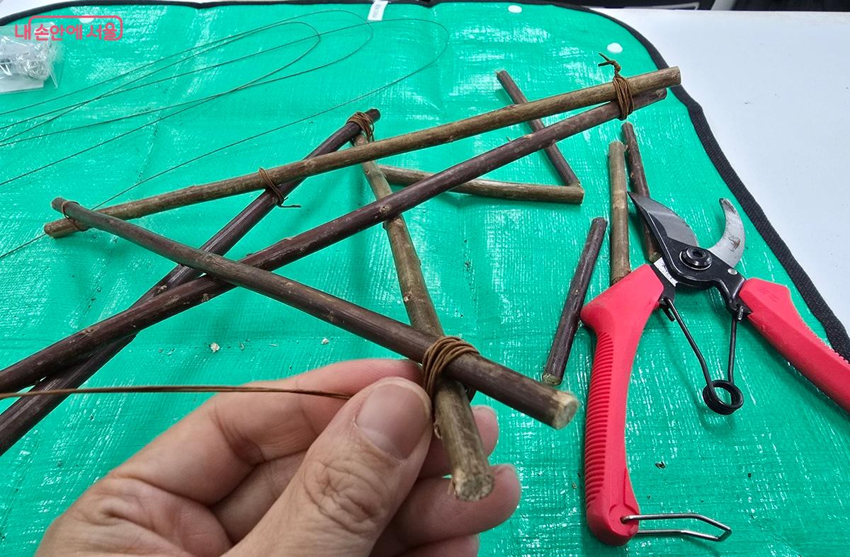 나뭇가지를 잘라서 와이어로 엮어 별 구조물을 만들고 있다. ©조성희