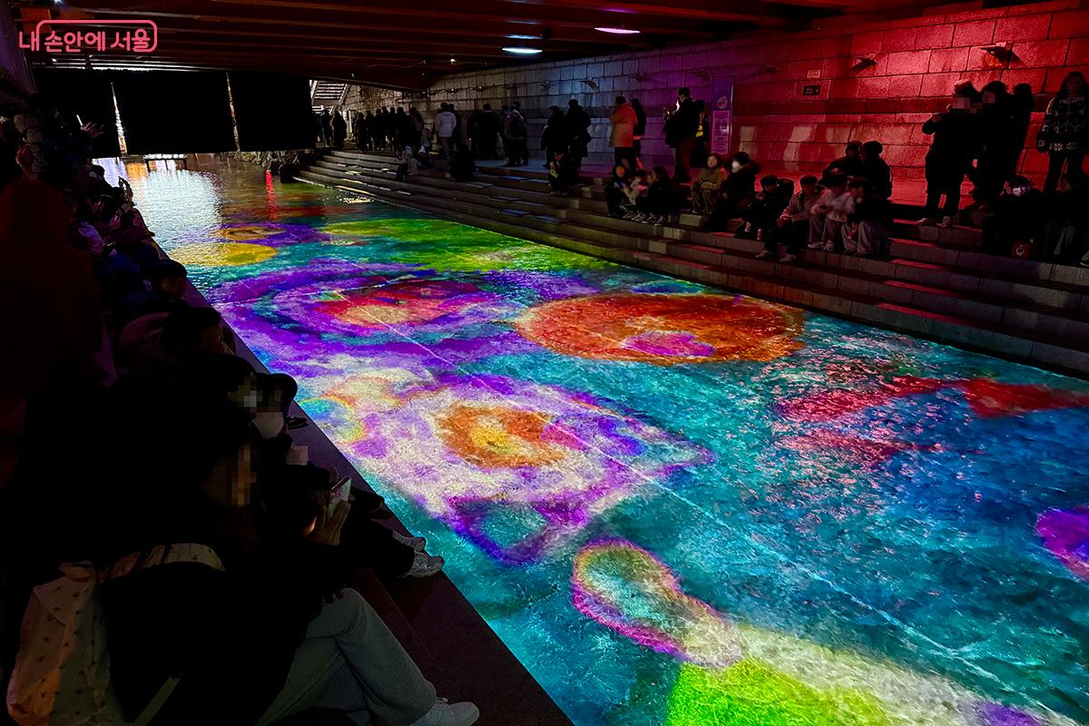 잠시 앉아 쉬며 청계천 물길 위 미디어아트를 즐기는 관람객들 &copy;김미정