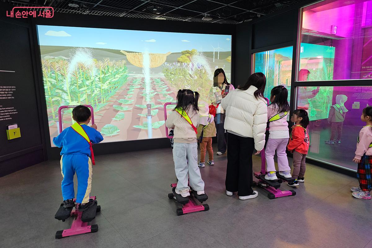 아이들이 직접 몸을 이용해 페달을 밟으며 농장의 식물들에게 물을 주는 체험을 하고 있다. &copy;백승훈