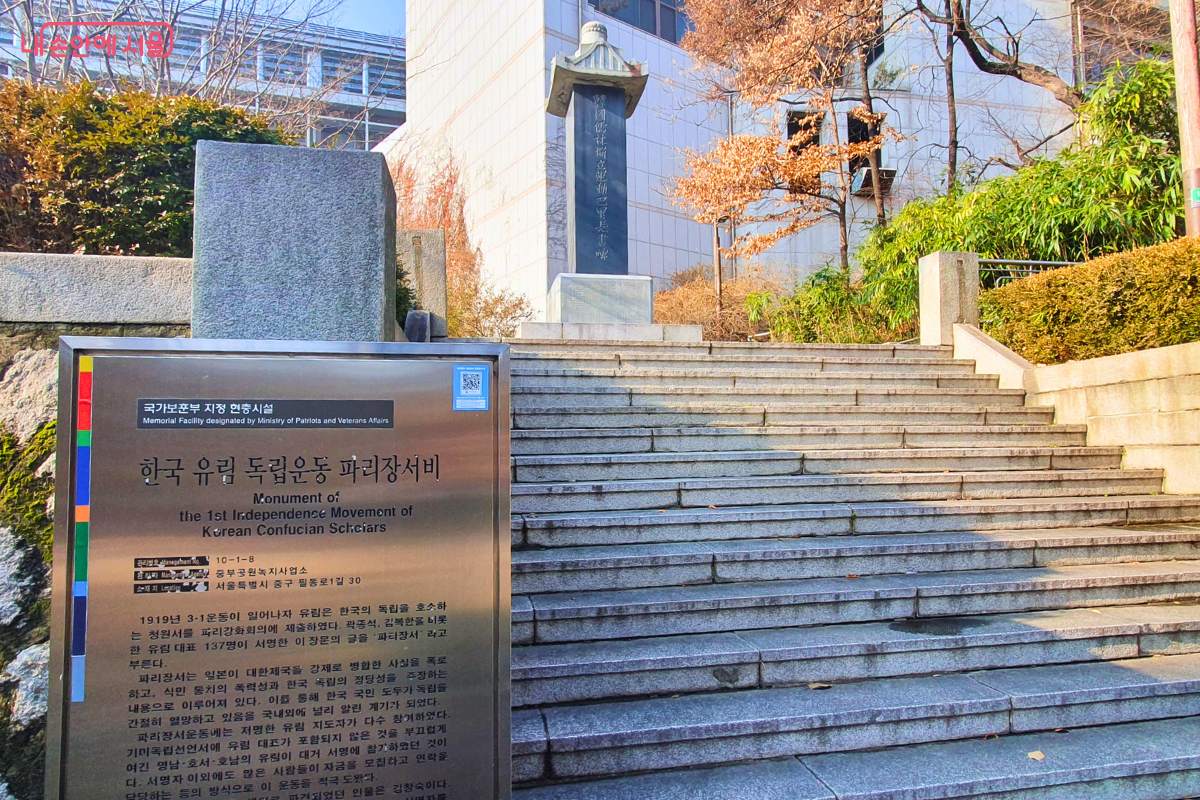 '한국 유림 독립운동 파리장서비'로 향하는 석조 계단의 모습이다. 계단 왼쪽 앞에는 국가보훈부 지정 현충시설임을 알리는 금속 안내판이 세워져 있으며, 1919년 당시 유림들이 파리강화회의에 독립 청원서를 제출한 역사적 사실이 상세히 기록되어 있다. 계단 위쪽으로는 높은 석비가 당당하게 서 있다. &copy;양정화