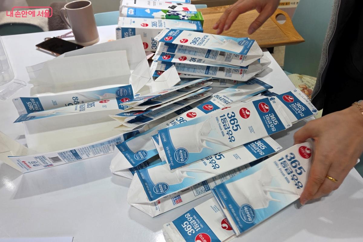 주민이 가져온 우유팩을 테이블 위에서 정리 중인 자원활동가 &copy;김미선