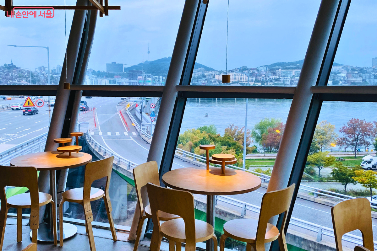 창밖으로 남산서울타워가 보이는 조망이다. 한남대교의 진입로와 굽이진 도로, 그리고 한강 변의 나무들이 어우러진 풍경이 유리창 너머로 시원하게 펼쳐진다. &copy;양정화