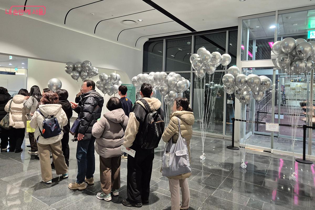 이벤트 선물로 준비된 풍선을 받기 위해 질서있게 줄을 서 있는 시민들의 모습