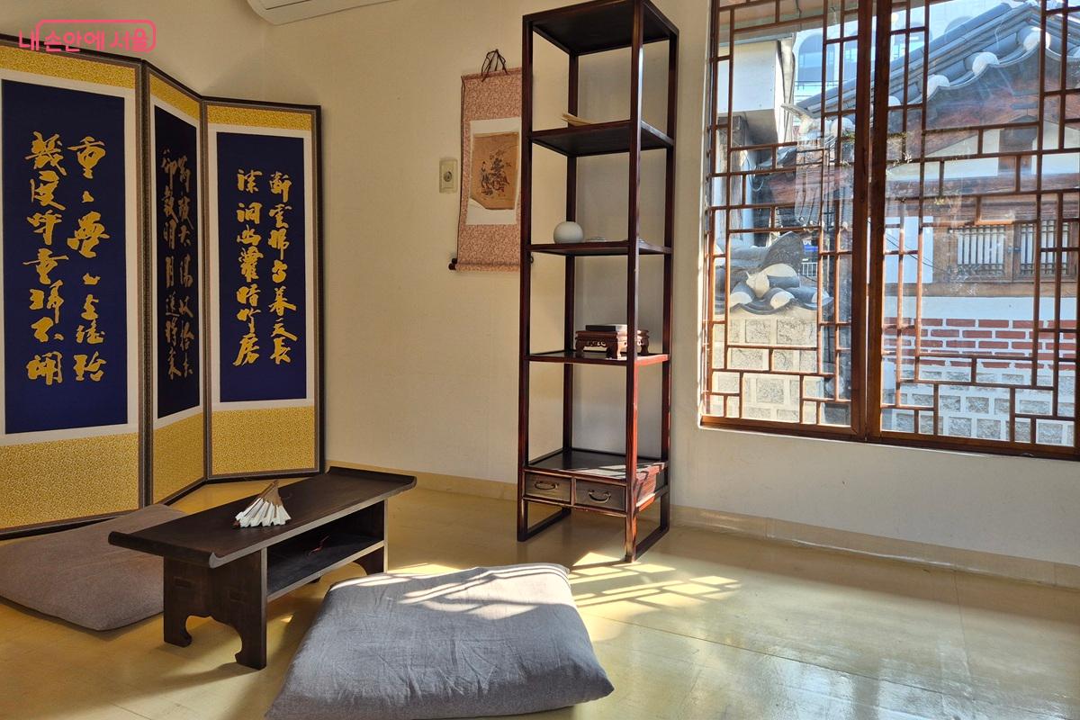 사랑채 내부 모습이다. 병풍과 탁자 및 방석, 수납장이 있고 뒤로는 '아'자 모양의 창호이 있다. &copy;마가은