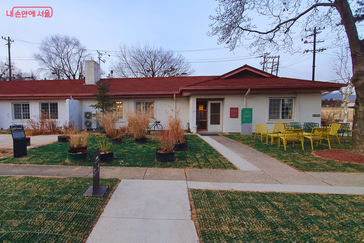 과거 장교 숙소로 쓰이던 붉은 지붕의 단층 주택과 마당 풍경이다. 노란색 철제 의자들이 놓여 있어 이국적인 분위기의 포토존을 형성하고 있다.