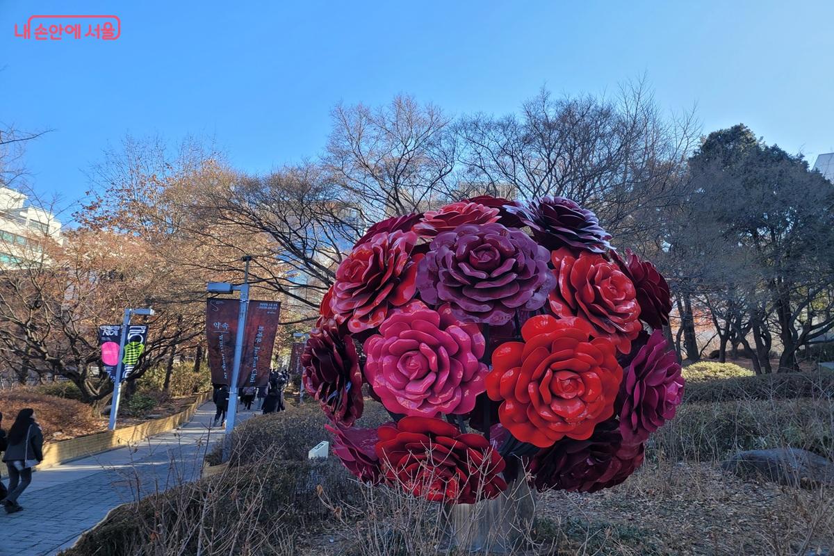 정동길 산책로에 설치된 붉은 장미 형태의 대형 조형물과 가로수가 보이는 모습.