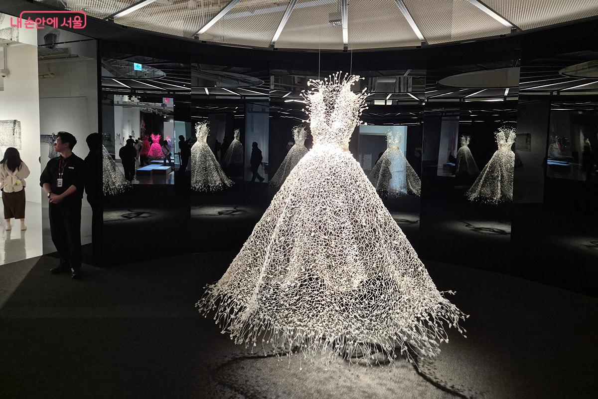 ‘백매(白梅)’ 드레스는 칠흑 같은 어둠 속에 홀로 빛나며, 마치 한겨울 밤 꿈속에 들어온 듯한 착각을 불러일으킨다.