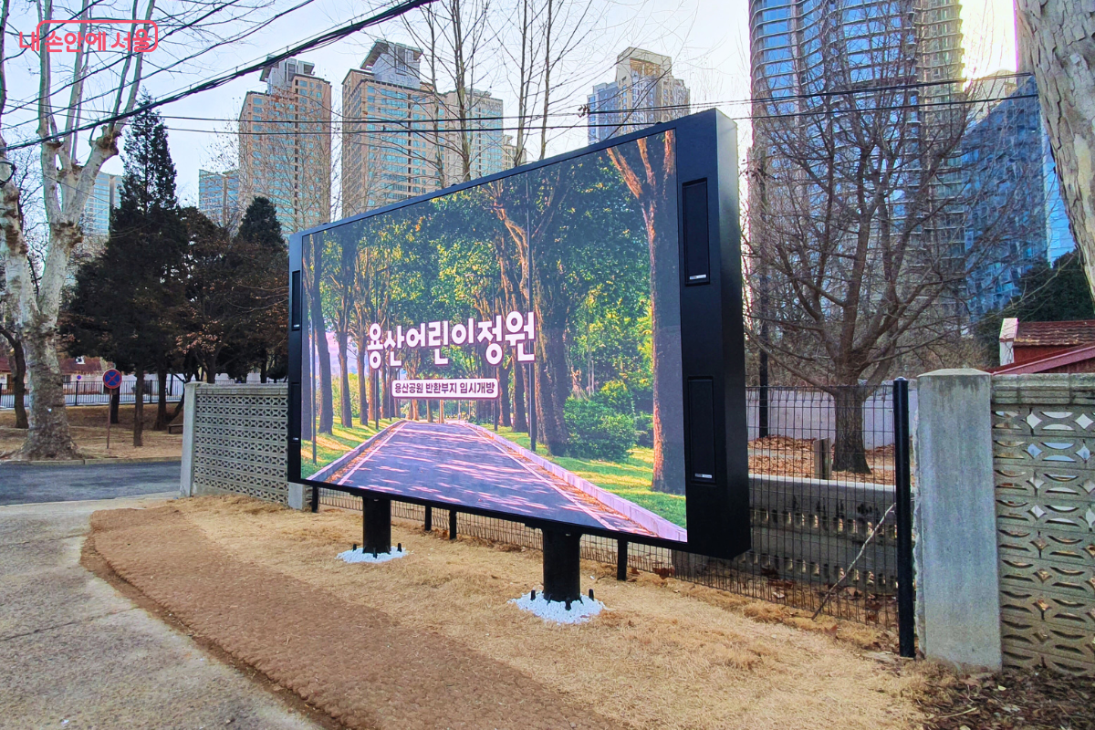 용산어린이정원 입구에 설치된 대형 LED 전광판이다. 화면에는 '용산어린이정원' 문구와 함께 푸른 나무가 우거진 정원 내부 산책로 영상이 선명하게 나오고 있다.