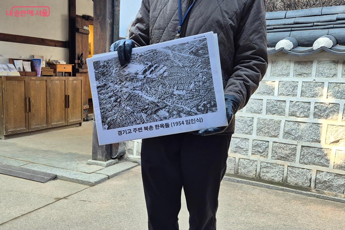 해설사가 북촌 한옥의 역사에 대해서 설명하고 있다. 1950년대 항공 사진을 보여주며, 'ㅁ'과 'ㄷ' 자 형태의 한옥에 대해 설명하고 있다. &copy;마가은