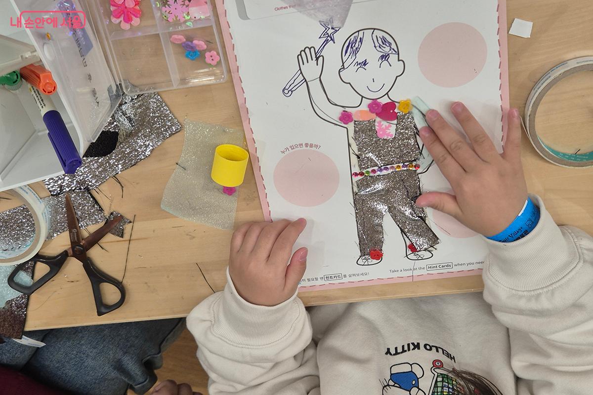 드로잉북 위에 반짝이는 천, 폼폼이 등을 붙여 옷을 입히는 콜라주 작업을 직접 체험할 수 있다.