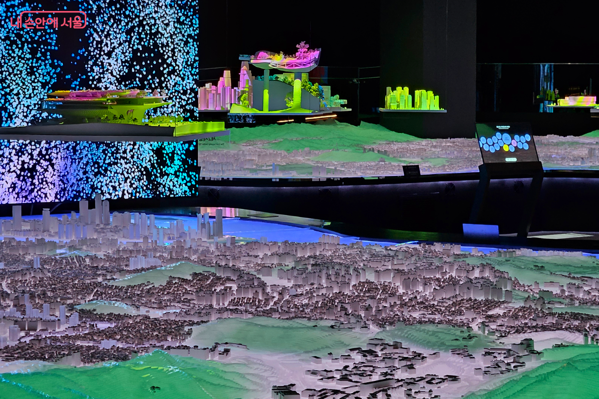 내 친구 서울 1관의 도시모형전시룸 사진. 서울 도시 모형 위로 다양한 건물 모형이 있다.