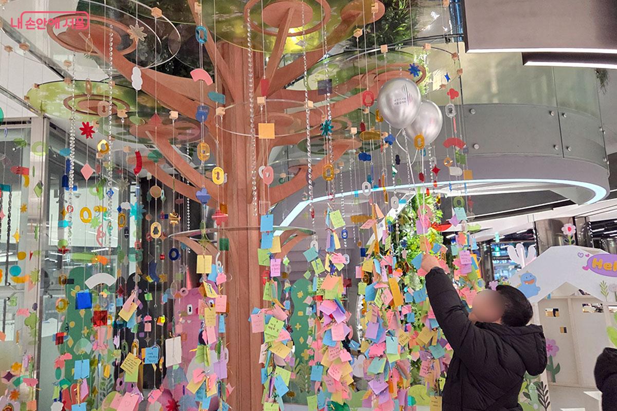 한 시민이 소원나무에 소원을 적어 매달고 있다. ⓒ이다현