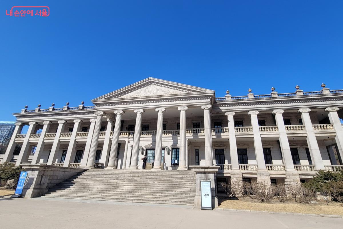 서울 덕수궁 석조전 건물 외관으로, 고전주의 양식의 기둥과 계단이 있는 흰색 석조 건물이 푸른 하늘 아래 서 있는 모습.
