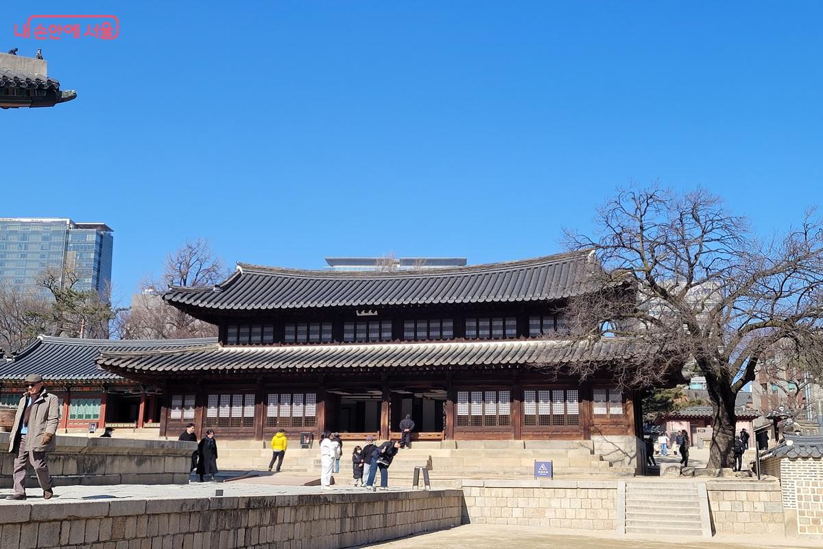 덕수궁 중화전 건물 전경으로 기와지붕을 얹은 목조건물이 마당과 함께 보이고 시민들이 관람하고 있는 모습.
