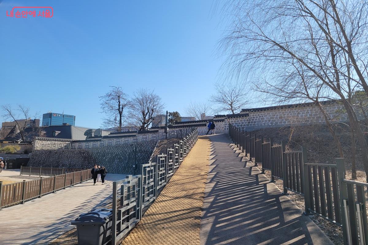 덕수궁 인근 고종의 길 산책로로, 돌담과 난간이 있는 경사 보행로를 시민들이 오르내리는 모습.
