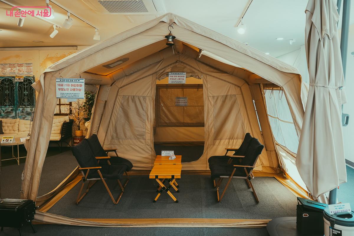 실내에 설치된 대형 베이지색 텐트와 캠핑용 의자, 테이블 &copy;김성무