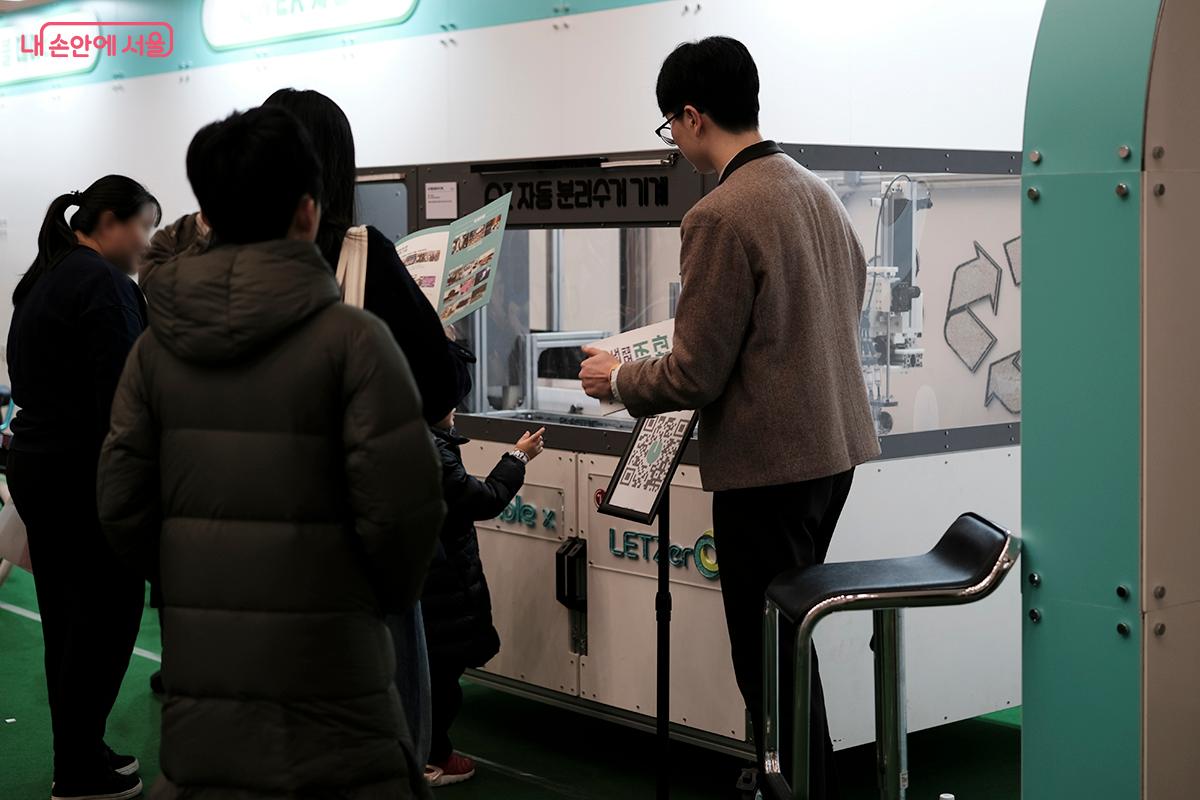 LG화학 '렛제로(LETZero)와 협업을 통해 제작한 AI 자동 분리수거 기계를 설명하고 있는 학생과 관람객들 ⓒ김아름