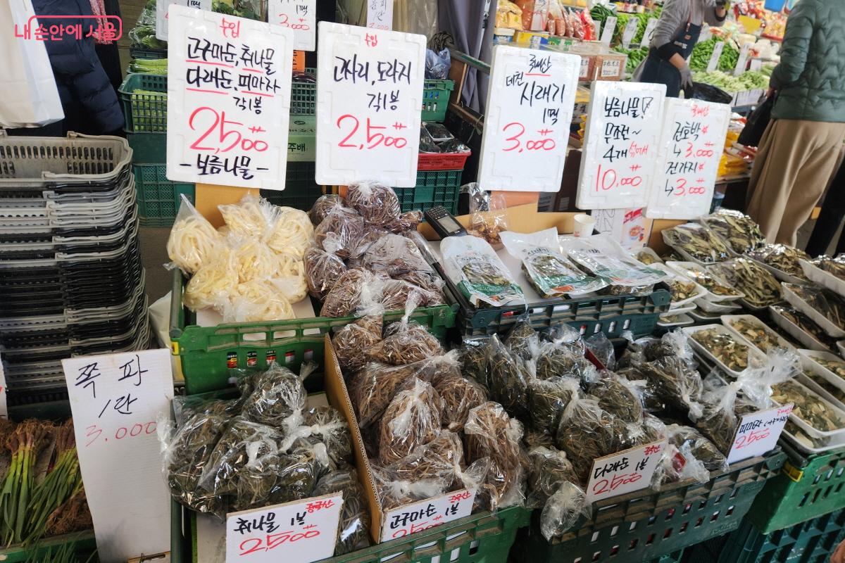 남구로시장 한 채소가게에 고구마순, 고사리, 도라지, 취나물, 쪽파 등 다양한 채소가 칸막이에 나뉘어 담겨 있다. 신선한 나물과 채소들이 판매를 위해 진열돼 있다.