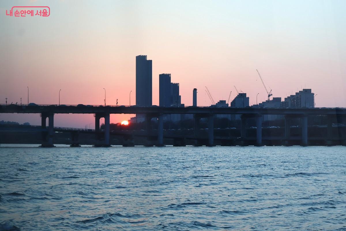 빌딩 숲 너머로 저무는 해와 층층이 겹쳐진 교량의 실루엣의 한강 정취 ⓒ이봉덕