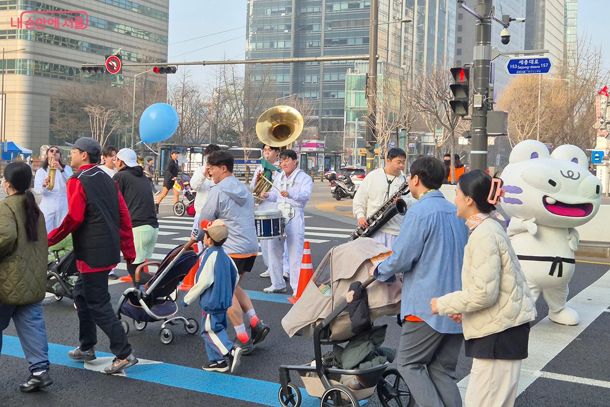 흰색 의상을 입은 브라스 밴드가 세종로를 지나는 참가자들을 응원하고 있다. ©정향선