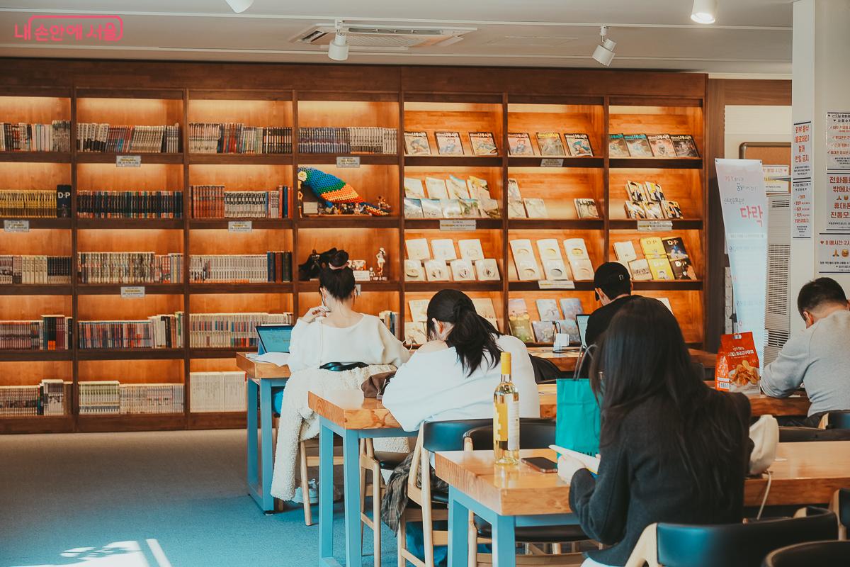 만화 서가를 배경으로 노트북을 하거나 책을 읽는 시민들의 뒷모습 &copy;김성무
