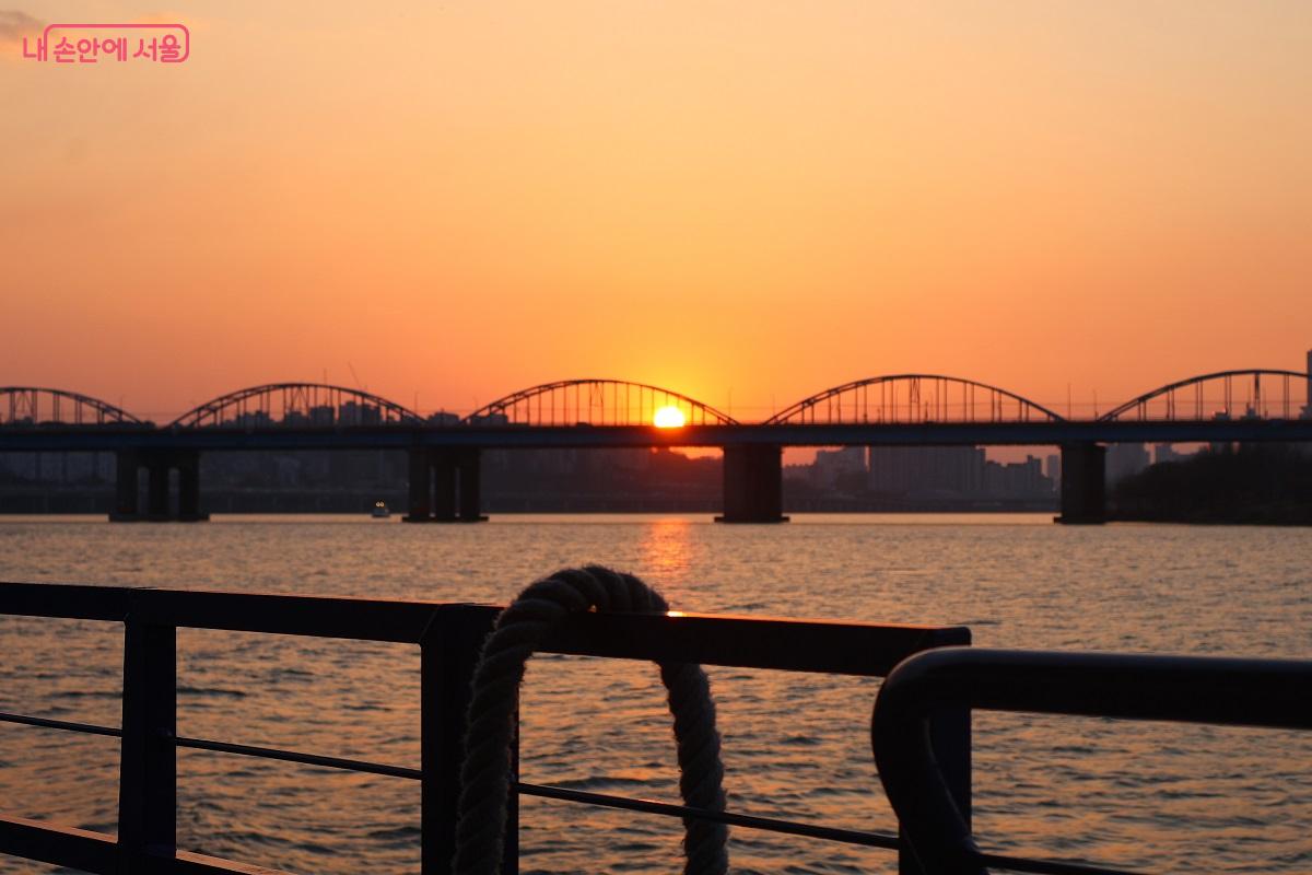 붉게 타오르는 석양이 한강 철교 아치 사이로 떨어지며 물길 위에 황홀한 풍경을 자아낸다. ⓒ이봉덕