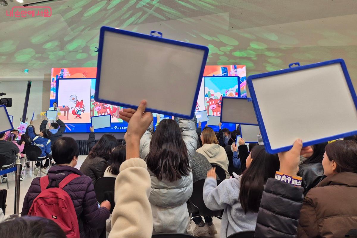 행사 참석자들이 문제에 대한 답을 화이트보드에 적고, 자신만만하게 화이트보드를 머리 위로 들고 있다. ⓒ마가은