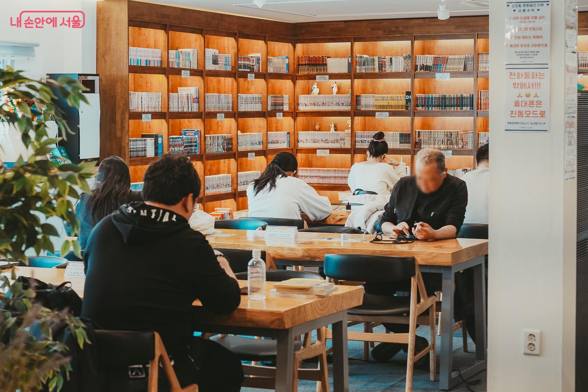 넒은 원목 테이블에 앉아 각자 책에 집중하고 있는 시민들의 모습 &copy;김성무