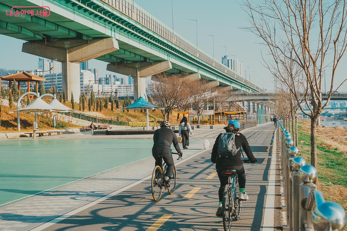 안양천 산책로에서 자전거를 타거나 반려견과 산책하는 시민들의 뒷모습 &copy;김성무