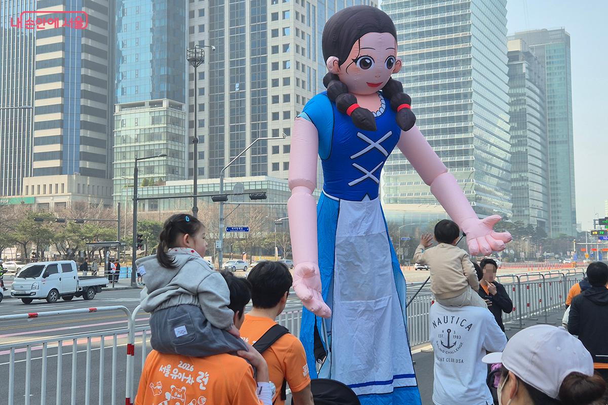 결승점에서 완주를 축하하는 대형 뮤지컬 인형 