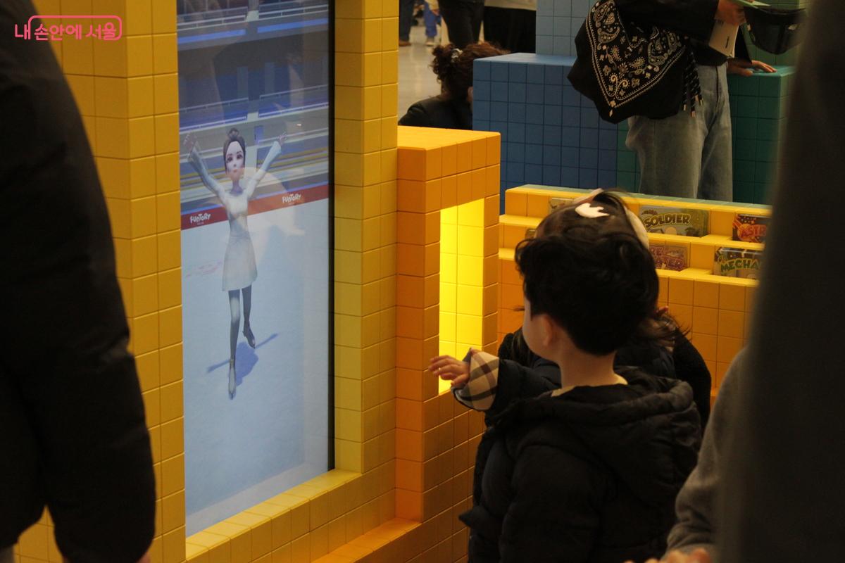 직접 그린 옷이 AI를 통해 영상으로 만들어진 모습을 보는 어린이 관람객
