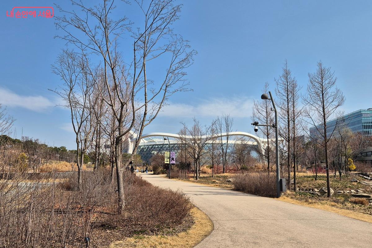 서울식물원의 온실이 숲 뒤로 위치하고 있다. 원형의 건축물로 유려한 곡선의 기둥들이 장식되어 있다. ⓒ마가은